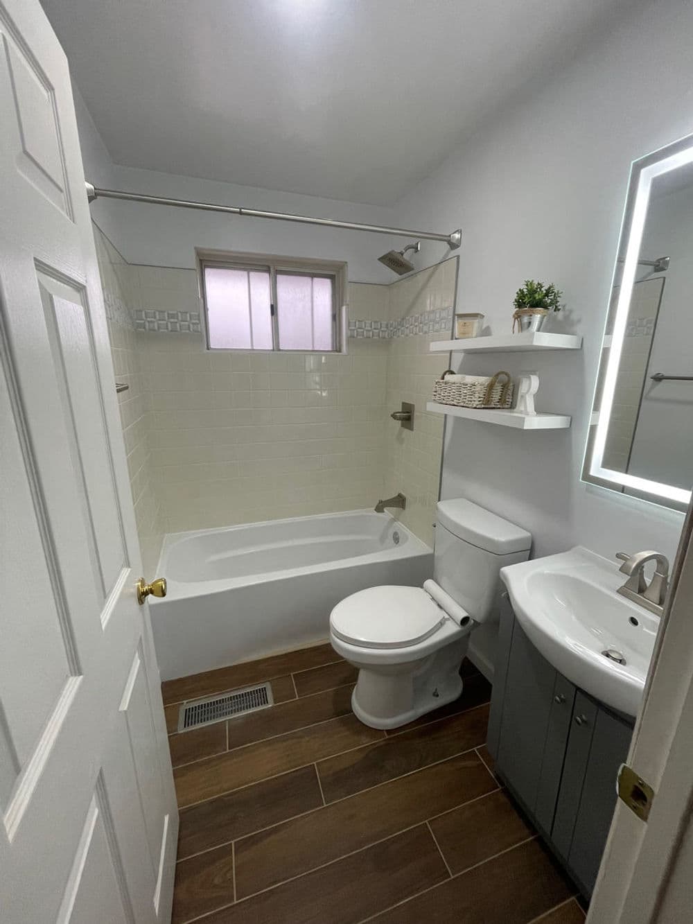 Modern bathroom featuring a bathtub, toilet, and sleek vanity with storage. Bright and clean design.