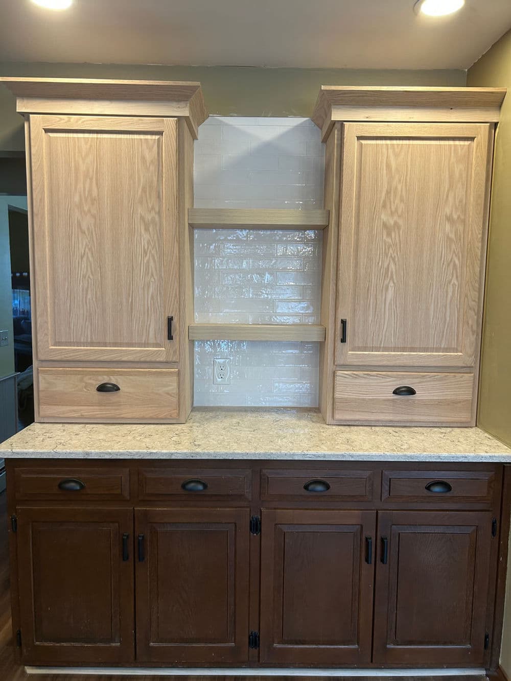 Modern kitchen cabinets with wood finish and open shelving above a countertop.