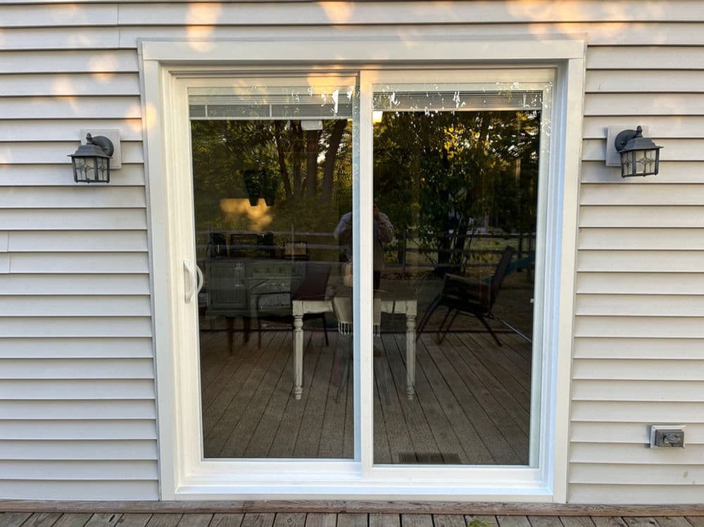 Two patio sliding doors with outdoor seating visible through the glass, framed by wall sconces.