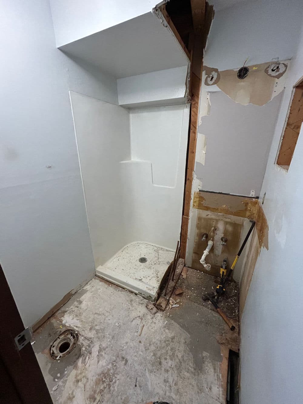 Renovation of a small bathroom with exposed walls, plumbing, and a shower area.