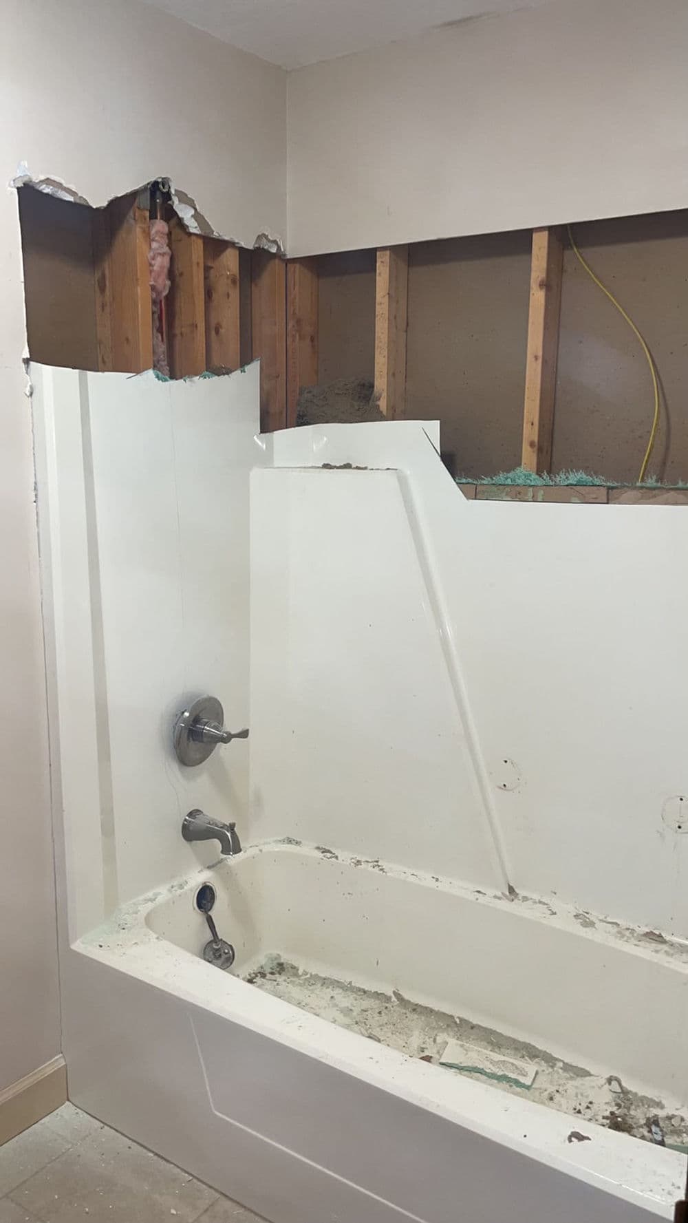 Renovation in progress: exposed bathtub area with incomplete wall and plumbing visible.