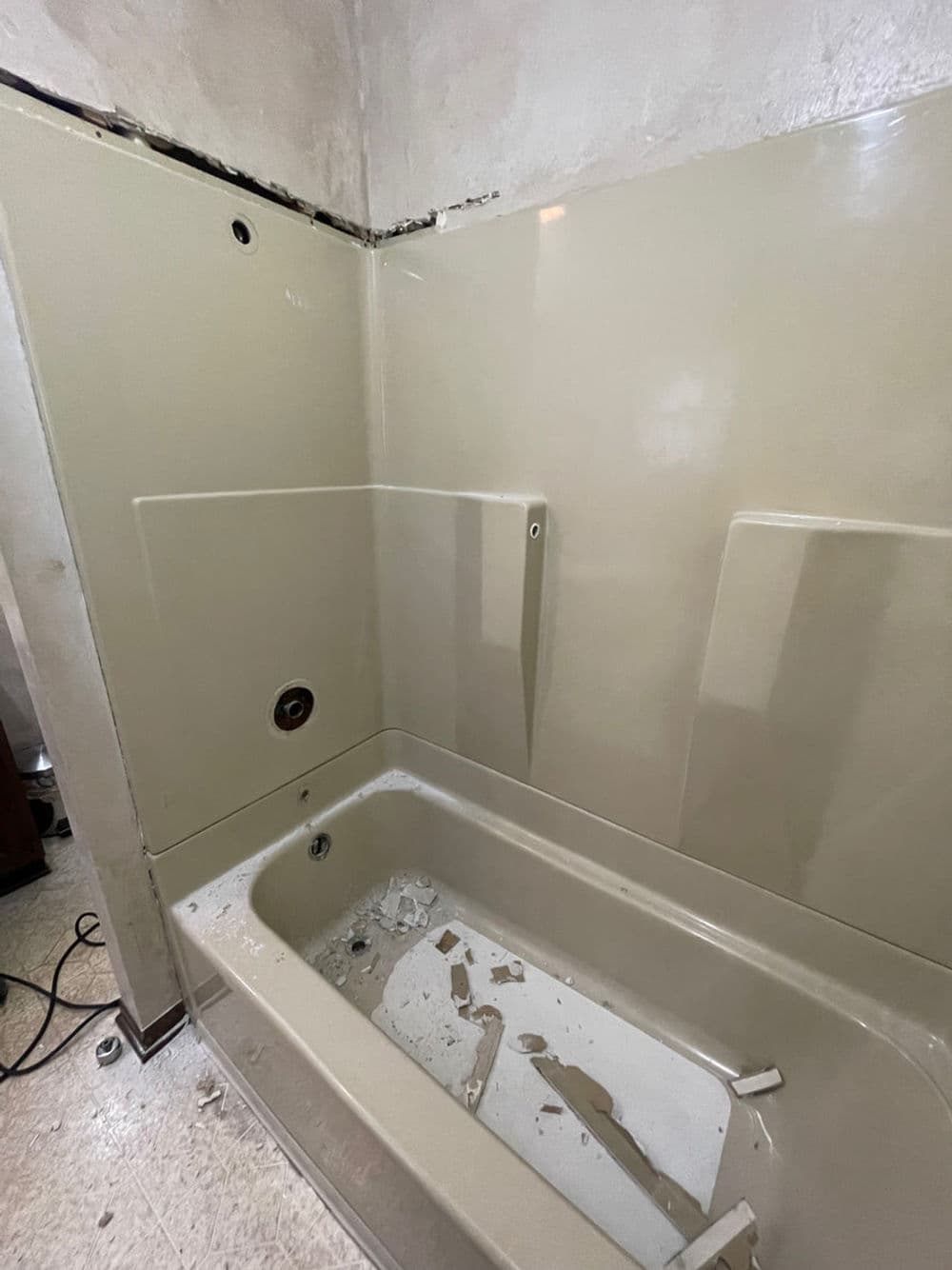 Renovation in progress: empty bathtub and wall panels in a bathroom remodel.